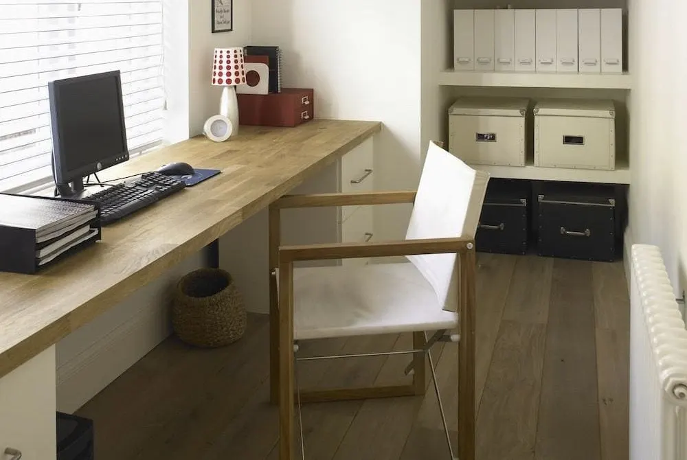 Plateau de bureau en chêne massif le long d’un mur, avec un écran et un fauteuil